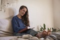 Woman sat writing her diary in bed