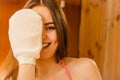 Woman in sauna with exfoliating glove. Skincare. Royalty Free Stock Photo