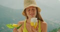 Woman savoring a Refreshing Lemon Treat Overlooking the Hills. The mountain breeze complements the zesty flavour, a