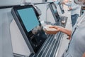 Woman scans barcode of lunch box for cashless payment at the self-service checkout in the supermarket. Such machines kiosks