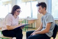 Woman school psychologist talking and helping student, male teenager