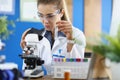 Woman scientist chemist looking through microscope and holding test tube