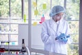 Woman scientist hand write note information in medical lab look at science microscope medical test, research biology chemistry. Royalty Free Stock Photo