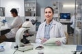 Woman scientist looking at camera working with microscope in laboratory Royalty Free Stock Photo