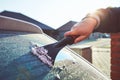 A woman scrapes frost off the front window of her car Royalty Free Stock Photo