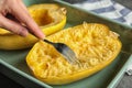 Woman scraping flesh of cooked spaghetti squash with fork on table Royalty Free Stock Photo