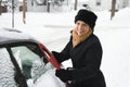 Woman scraping ice off car.