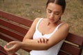 Woman scratching arm with insect bite outdoors