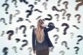 Woman scratching head and looking at blurred question marks Royalty Free Stock Photo