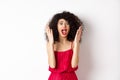 Woman scream in panic, wearing red dress and shouting at camera with anxious face, standing over white background