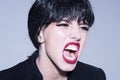 Woman screaming on grey background. Angry girl concept. Girl on scandalous shouting face wears formal jacket.