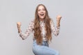 Woman screaming for joy and raising high her fists celebrating successful winning incredible victory Royalty Free Stock Photo