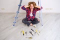 A woman screams because of the difficulty of carrying out repairs on her own. Laid out construction tools on the floor