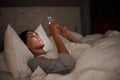 Woman, scrolling and phone for social media, bed and relaxation under blankets in pajamas to sleep. Female person Royalty Free Stock Photo