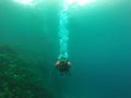 Woman scuba diving under crystal clear water with tank equipment, fins, snorkel, regulator, vest and pressure gauge having fun whi Royalty Free Stock Photo