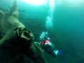 Woman scuba diving under crystal clear water with tank equipment, fins, snorkel, regulator, vest and pressure gauge having fun whi Royalty Free Stock Photo