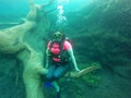 Woman scuba diving under crystal clear water with tank equipment, fins, snorkel, regulator, vest and pressure gauge having fun whi Royalty Free Stock Photo