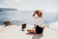 Woman sea laptop yoga. Business woman freelancer in yoga pose working over blue sea beach at laptop and meditates. Girl Royalty Free Stock Photo