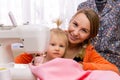 Woman seamstress engaged with daughter interrupting work Royalty Free Stock Photo