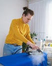 Woman seamstress ironing orange fabric while working at her workplace Royalty Free Stock Photo