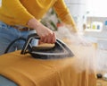 Woman seamstress ironing orange fabric while working at her workplace Royalty Free Stock Photo