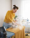 Woman seamstress ironing orange fabric while working at her workplace Royalty Free Stock Photo