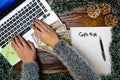 Woman searching for Christmas gifts on her laptop. Christmas decorations on wooden table. Christmas concept. Money and gift list Royalty Free Stock Photo