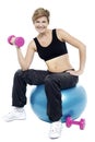 Woman seated on fitness ball doing dumbbells Royalty Free Stock Photo