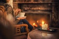Woman seating near fireplace and drinking cup of coffee and eating beatiful winter dessert with chocolate, product photography for
