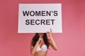 Woman is a secret. Young woman covering face with poster and ge