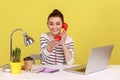 Woman secretary making calls on landline telephone working on laptop sitting at office. Royalty Free Stock Photo