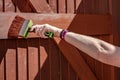 Woman seen painting a timber built gated entrance with a large, timber paintbrush.