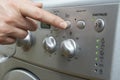 Woman Selecting Economy Program On Washing Machine To Save Energy