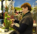 Woman seller arranging bouquet of flowers at the counter of the flower shop. Kyiv, Ukraine