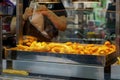 Woman selling churros in a traveling churreria at a fair. Food made with water, flour, oil and salt. They can be in the shape of