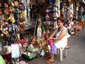 A woman sells assorted religious items to tourists in her stall beside a church