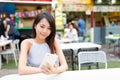 Woman sending sms on cellphone at outdoor restaurant Royalty Free Stock Photo