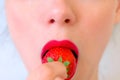 Woman with sensual red lips and freckles is eating strawberry, lips closeup. Royalty Free Stock Photo