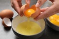 Woman separating egg yolk from white over bowl at grey table, closeup Royalty Free Stock Photo