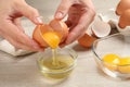 Woman separating egg yolk from white over glass bowl at wooden table, closeup Royalty Free Stock Photo