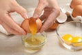 Woman separating egg yolk from white over glass bowl at wooden table, closeup Royalty Free Stock Photo