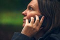 Woman with serious face expression talking on phone in park Royalty Free Stock Photo