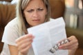 Woman with serious face reads doctor& x27;s prescription while sitting on sofa. Royalty Free Stock Photo