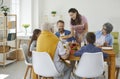 Woman serve the table for a large family in the dining room with a smile on her face.