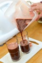 Hands serving the dark colored juice of vegetables and fruit made by the extractor