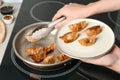 Woman serving freshly cooked delicious gyoza on plate in kitchen, closeup