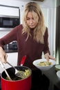 Woman serving prepared pasta in bowl at kitchen counter