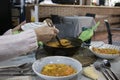 Woman serving a soupy rice with a saucepan