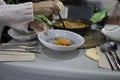 Woman serving a soupy rice with a saucepan