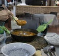 Woman serving a soupy rice with a saucepan